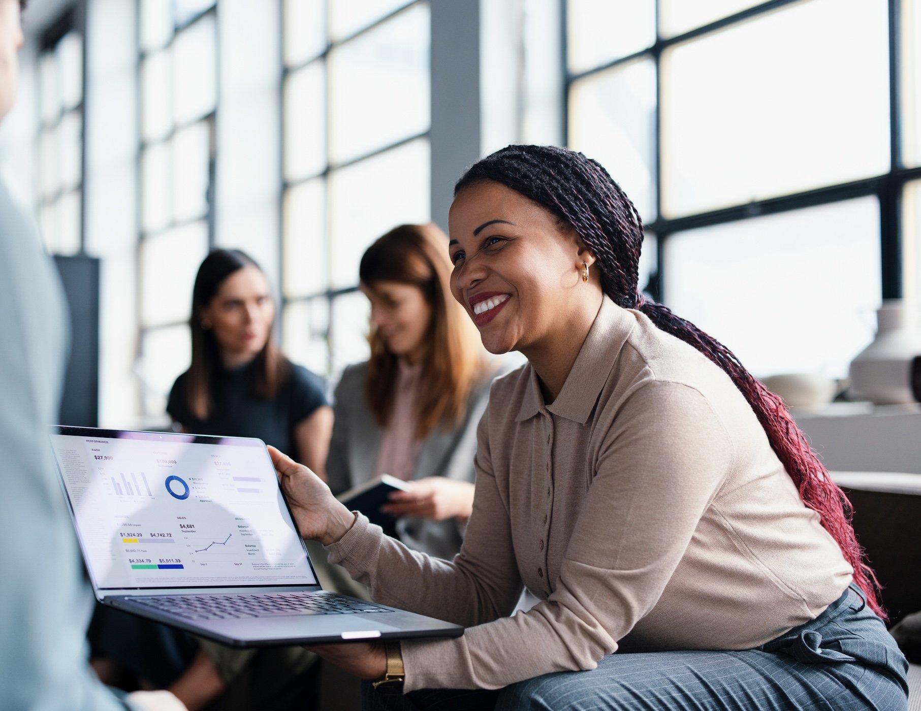 A woman smiling and holding a laptop